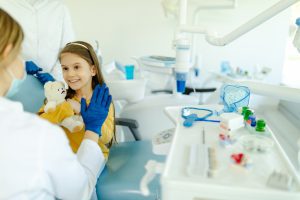 Female doctor is giving hi five to little girl after a successful dental examination.